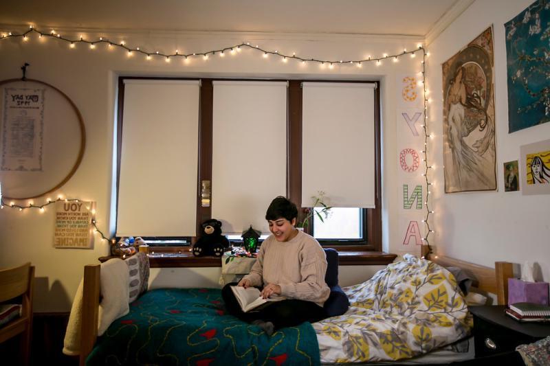 Student sitting on bed in dorm room